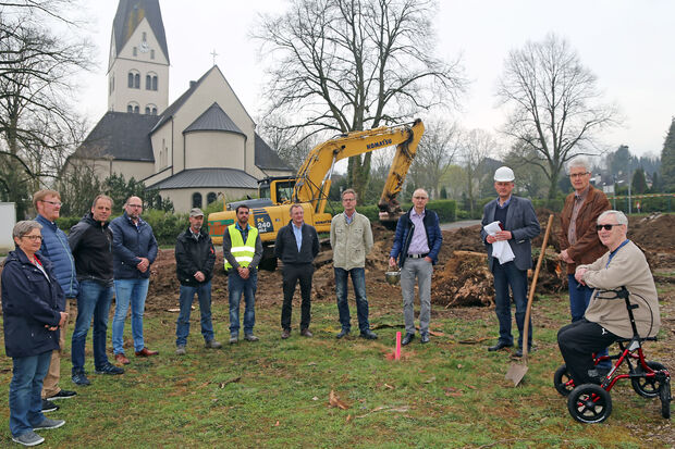 Katholische Geistliche, Kirchenvorstandsmitglieder und Bauleute beim symbolischen ersten Spatenstich im Rahmen des Pfarrheim-Neubaus an der Friedhofstraße (von links): Lydia Münstermann, Vikar Alexander Plümpe, Architekt Stephan Voß vom Mendener Architekten- und Ingenieur-Büro „Hilker + Jochheim“, Dirk Heggemann (Ziegelei-Vertreter), Erich Brumm und André Gomes vom Tiefbau-Unternehmen Driller, Guido Laarmann–Quante, Bernd Stute, Franz–Josef Schulte, Pfarrer Thomas Metten (mit Stola und Sturzhelm), Peter Hesse und Horst-Dieter Pieper. Im Hintergrund: die katholische St.-Antonius-Pfarrkirche. FOTO: ANDREAS DUNKER 