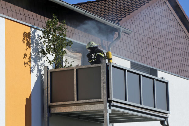 Qualm kommt aus der brennenden Wohnung im Wickeder Osten. Ein Feuerwehrmann mit Atemschutz steht auf dem Balkon. FOTO: CARINA WESTERWELLE